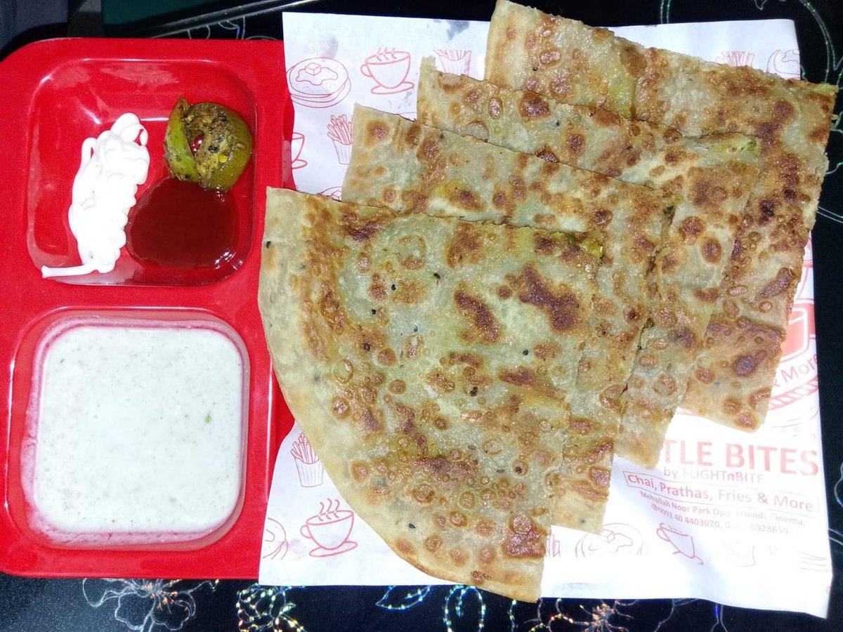 Paratha sliced into wedges, served with raita and house chutneys