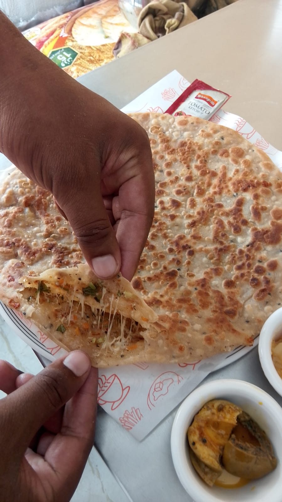 Freshly made paratha served on paper with three house chutneys